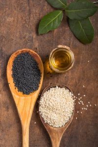 sesame seeds in wooden spoons and a small jar of oil