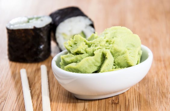 Wasabi in a bowl next to two sushi rolls